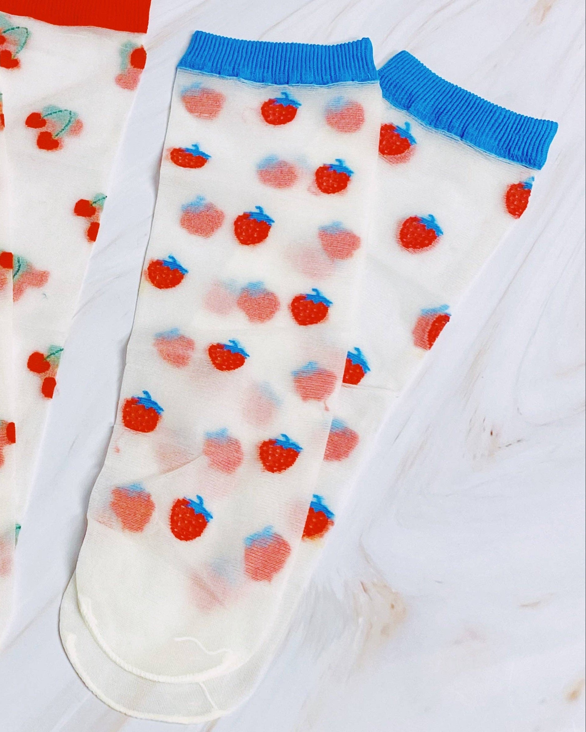 Two pairs of socks with fruit patterns on a light background
