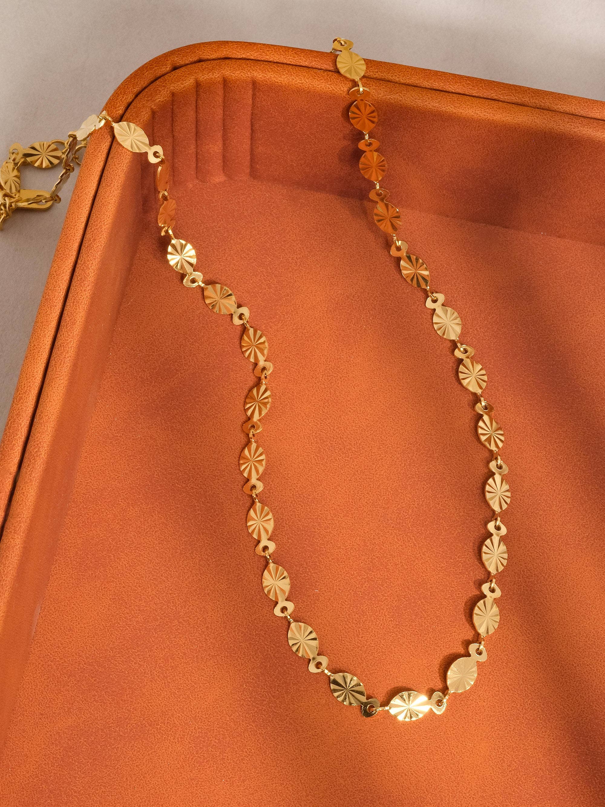 Gold necklace on an orange fabric background