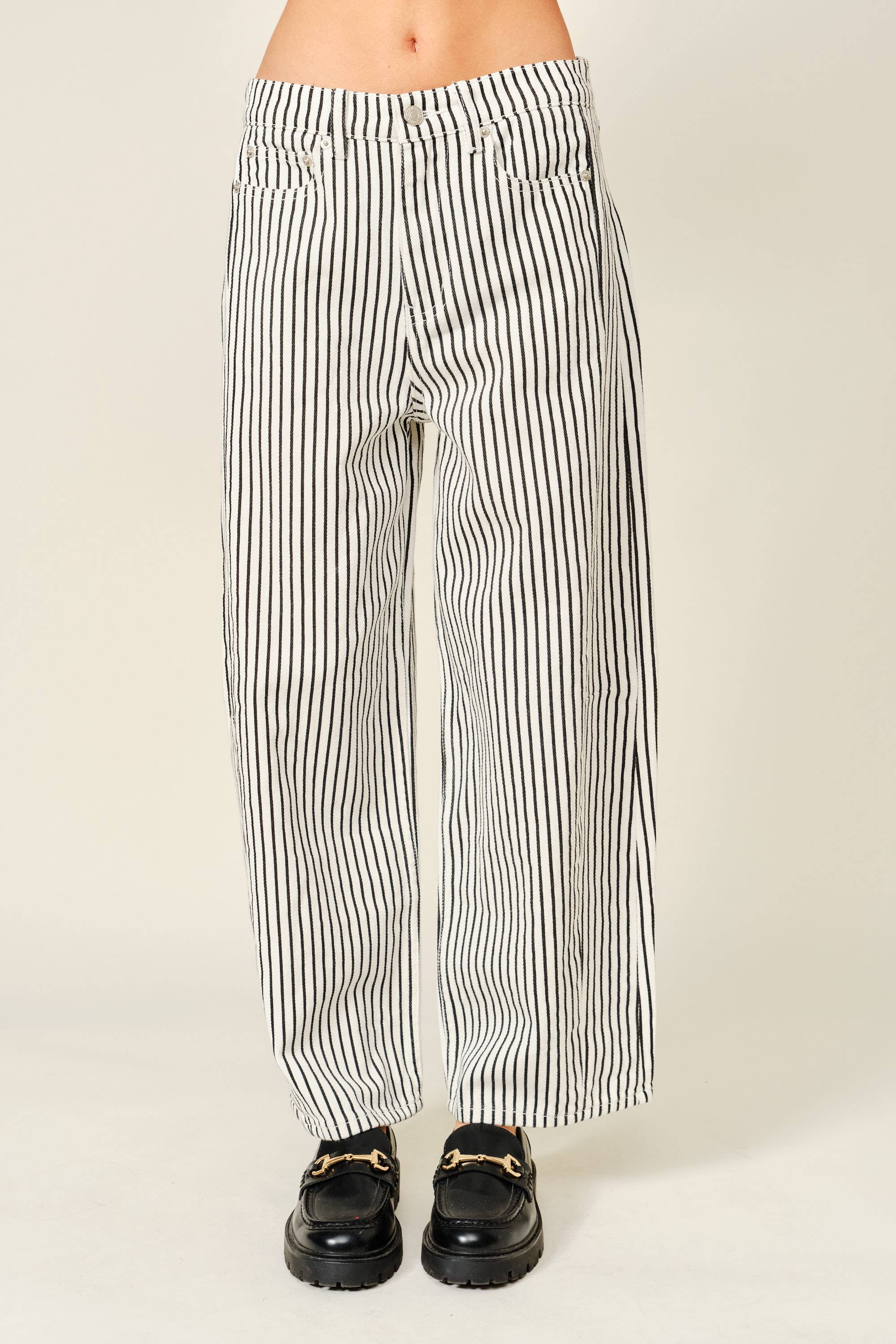 Black and white striped pants worn by a person on a plain background