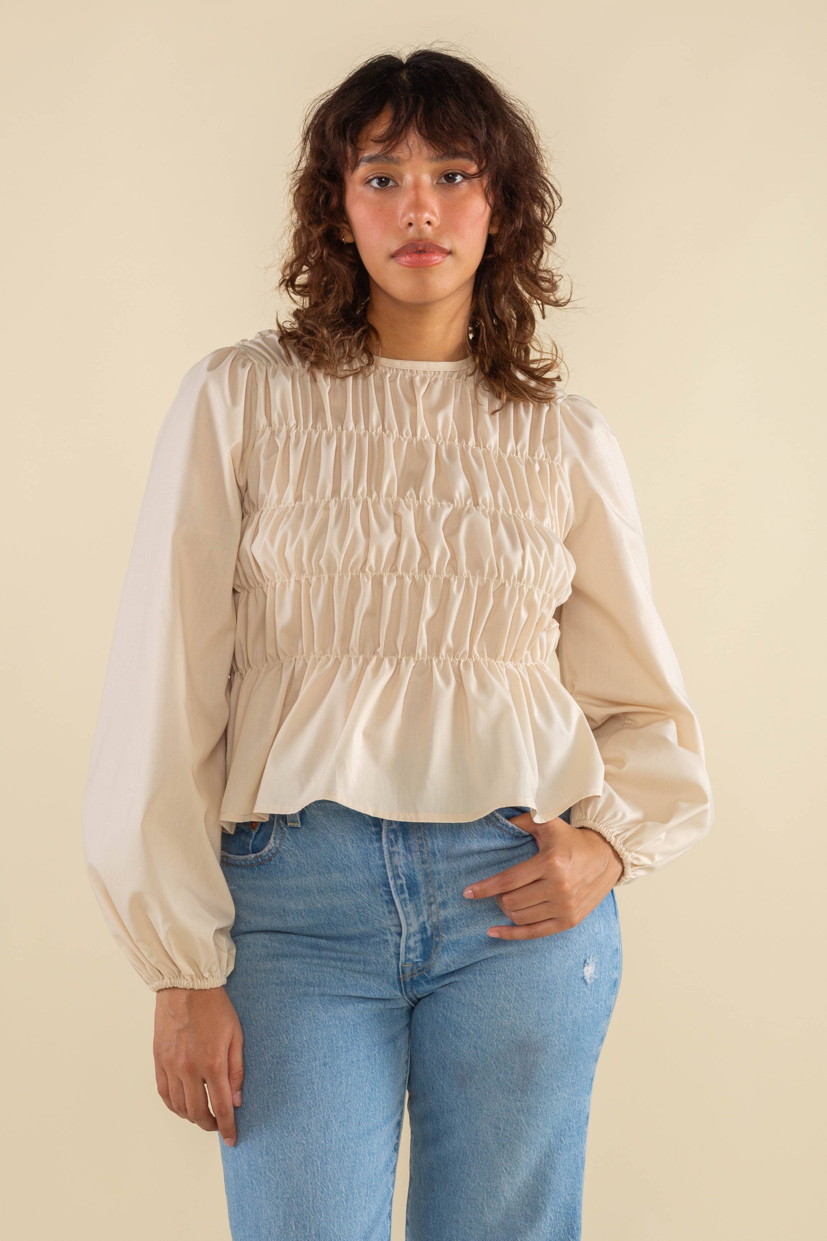 Woman wearing natural cream white color, bubble long sleeve, shirred, peplum style top