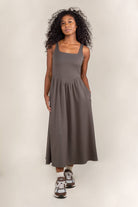 Woman wearing olive colored, midi dress, with corset bodice detail