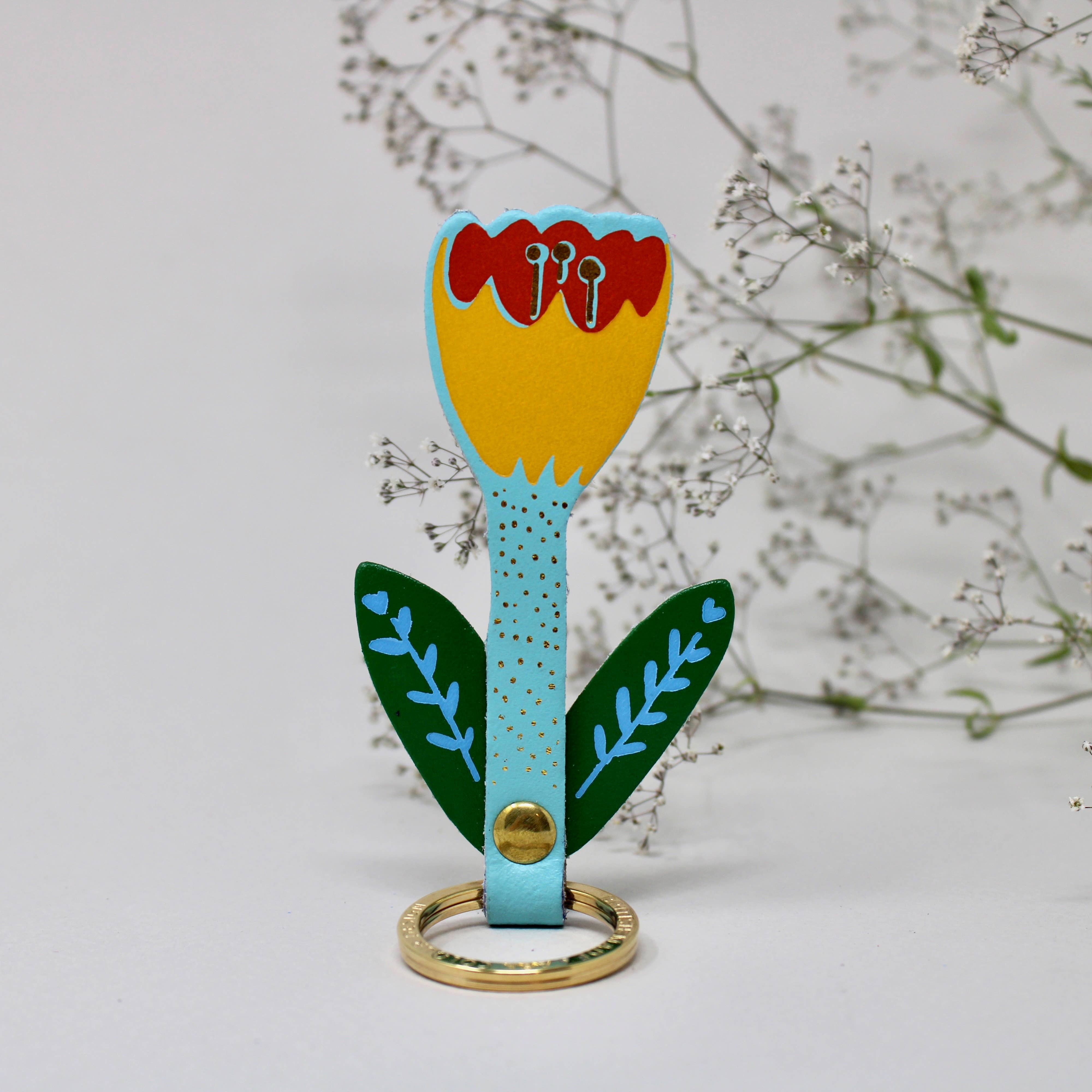 Colorful tulip keychain behind foliage background. 
