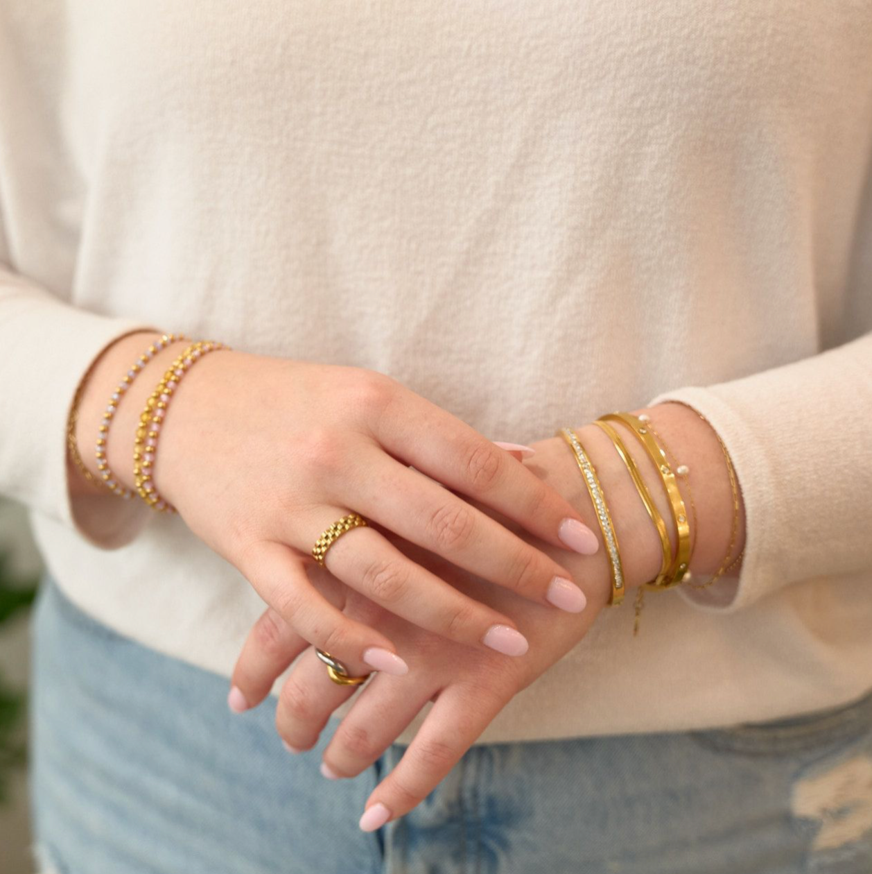 Woman wearing bracelets and rings including Gold, waterproof, tarnish free, watch band ring on a white background