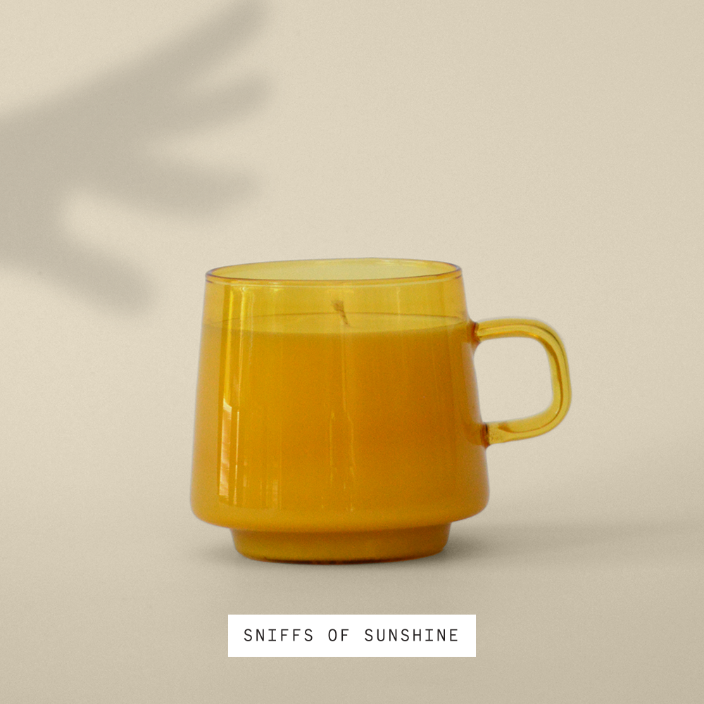 candle in Yellow opaque reusable mug sitting in the sun against a cream colored wall