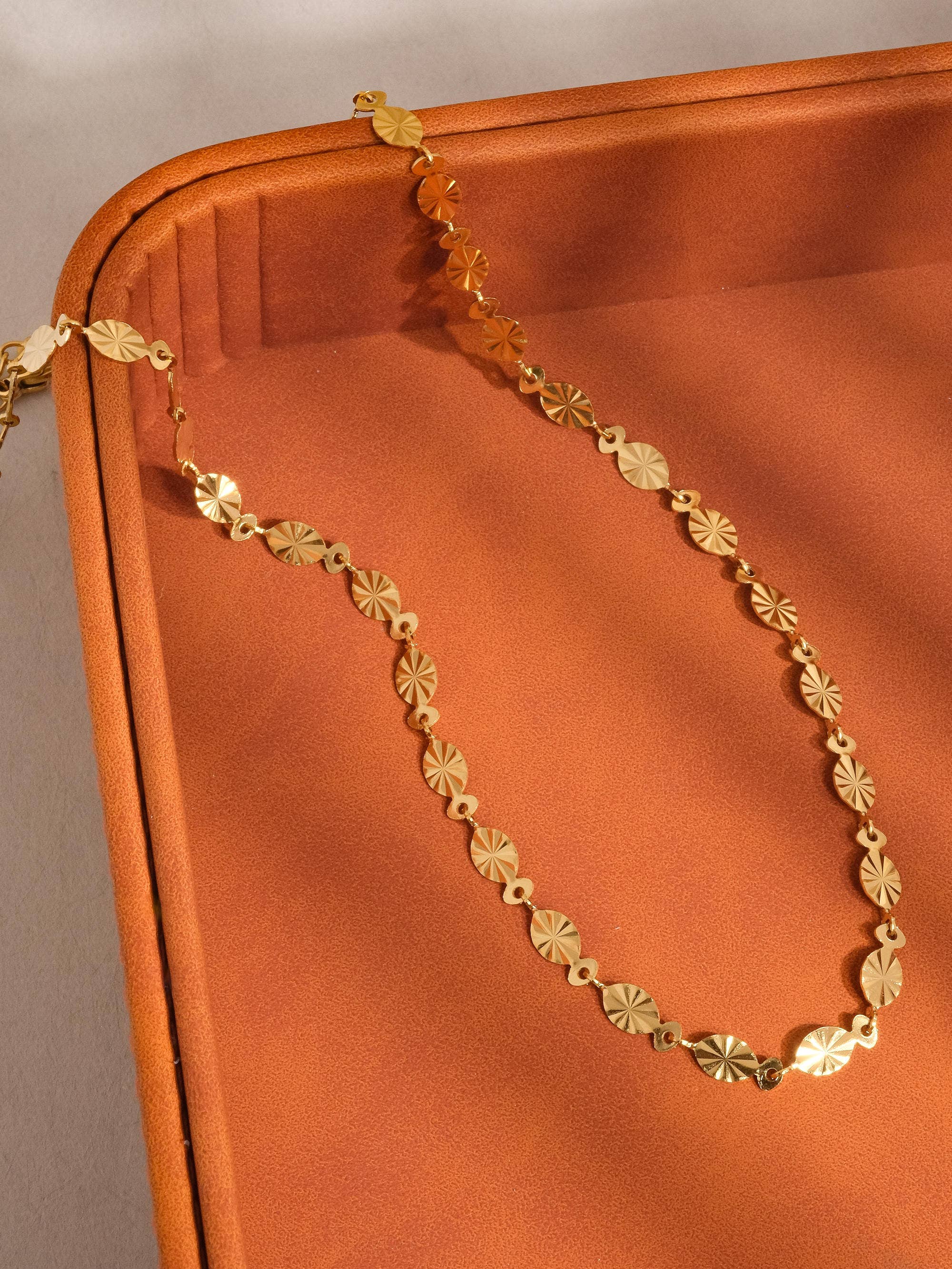 Gold chain on a textured orange surface