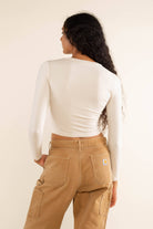 Woman wearing white, long sleeve, tight, crew neck, top with khaki carhart jeans
