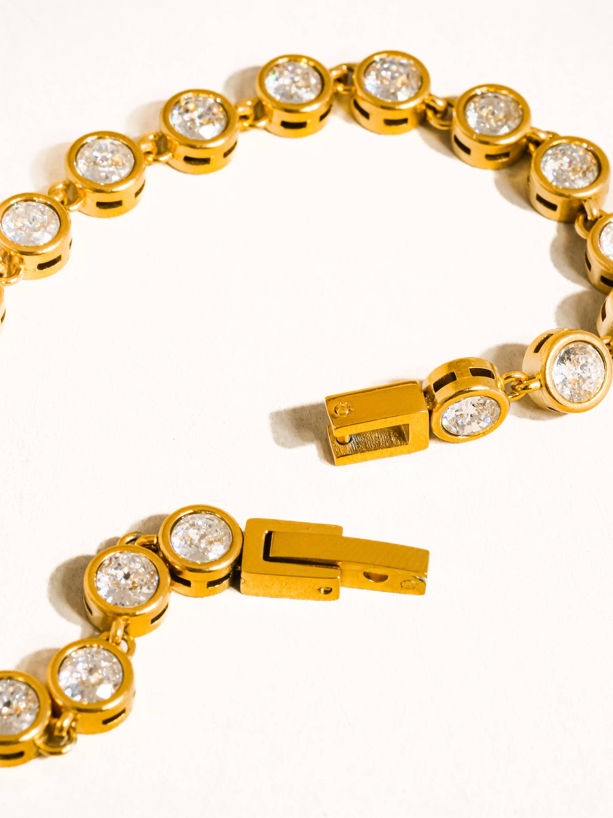 Gold bracelet with clear gemstones on a white background