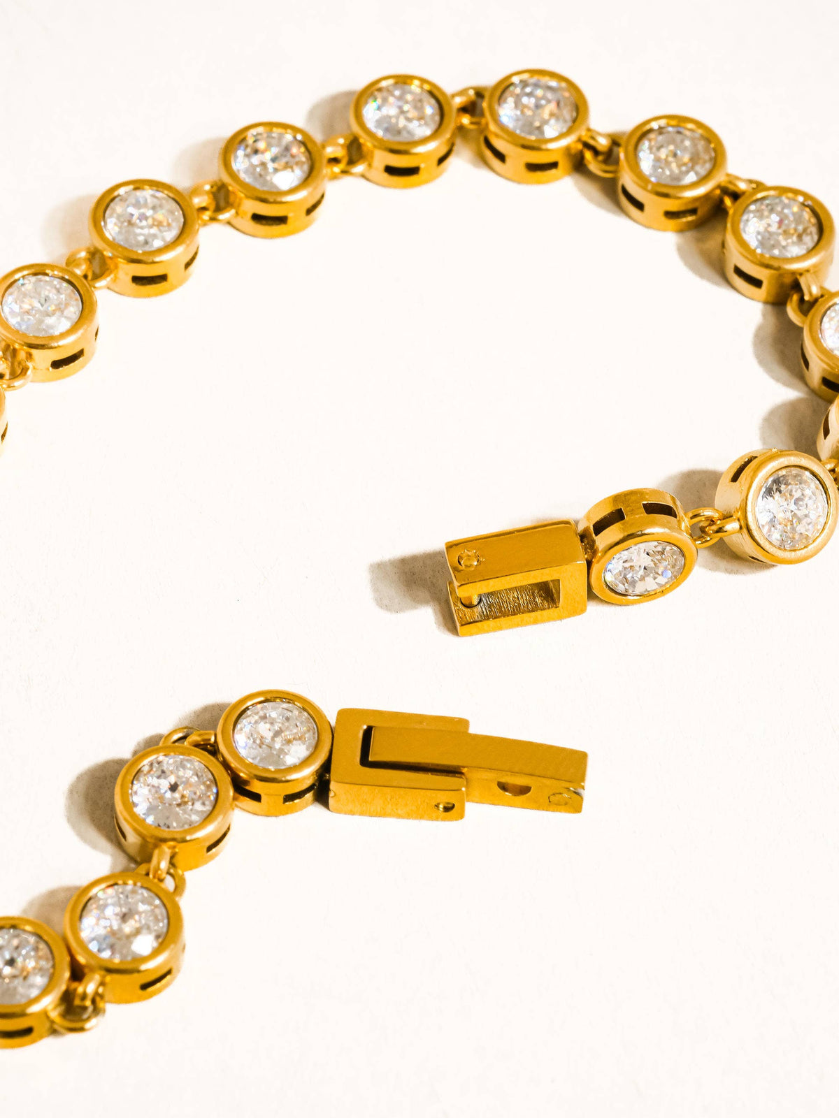 Gold bracelet with clear gemstones on a white background