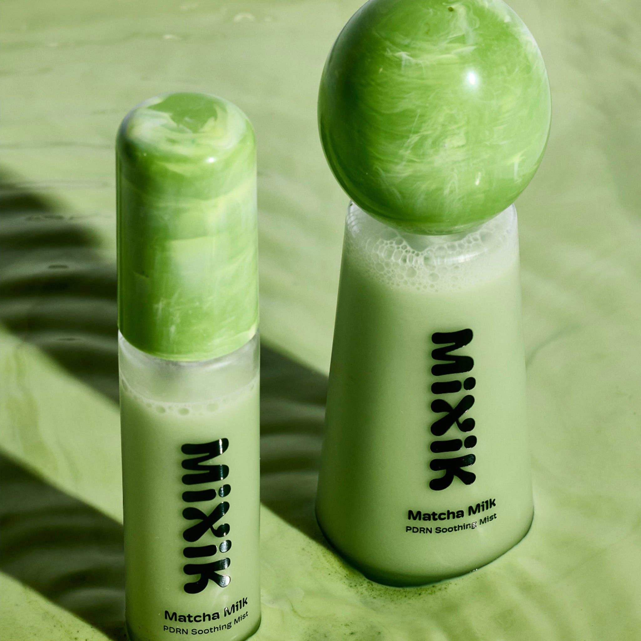 Two bottles of MIXIK Matcha Milk on a green surface with a marble effect.