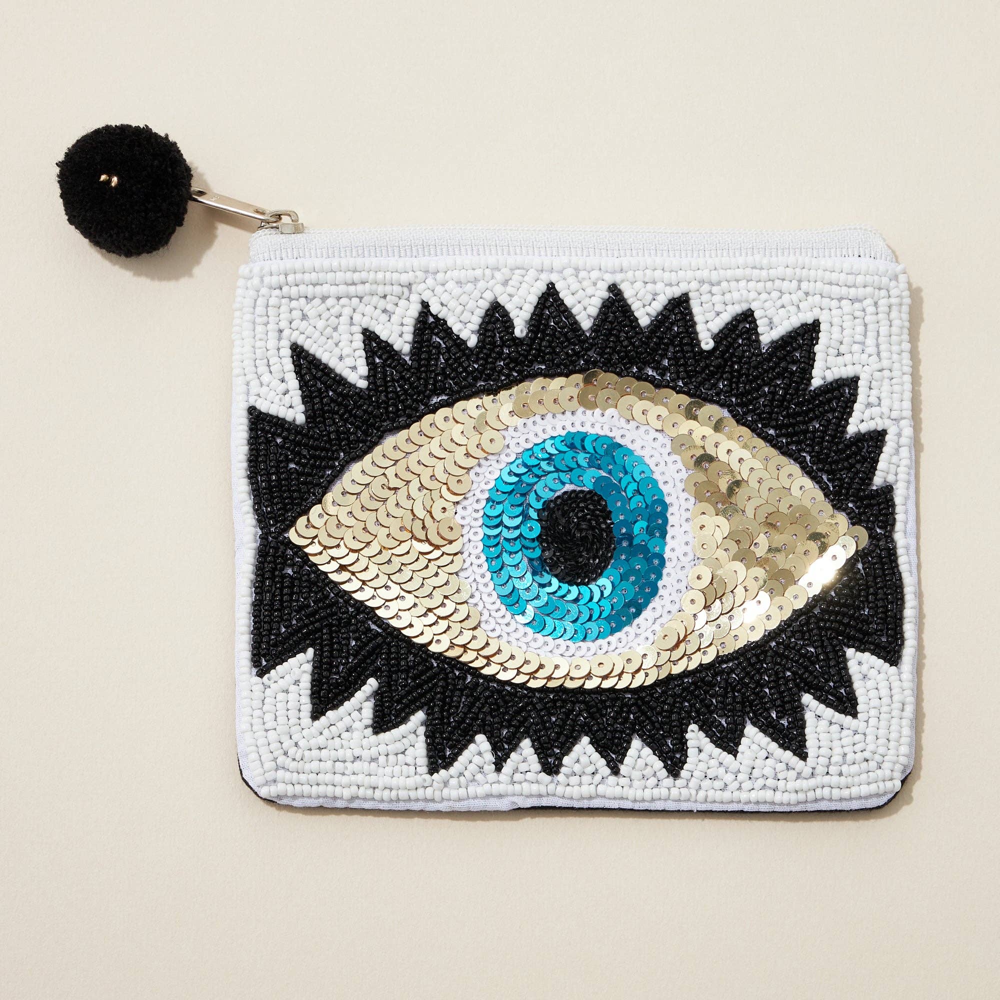 Pouch with eye design featuring sequins on a beige background