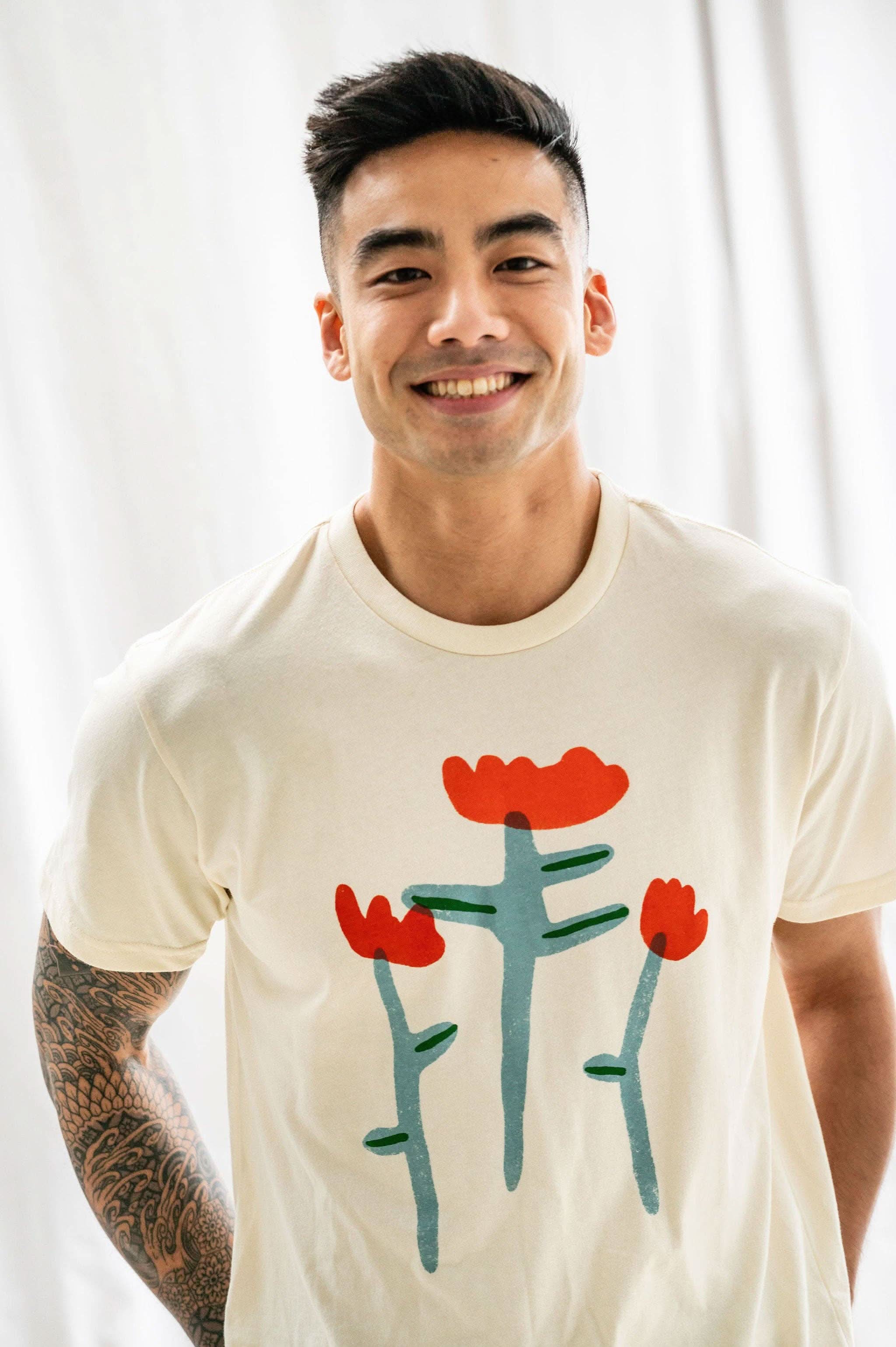Man smiling wearing Cream white Tshirt tee with three red tulip doodles on the Tshirt 