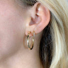 Woman wearing gold medium sized tube hoop earrings