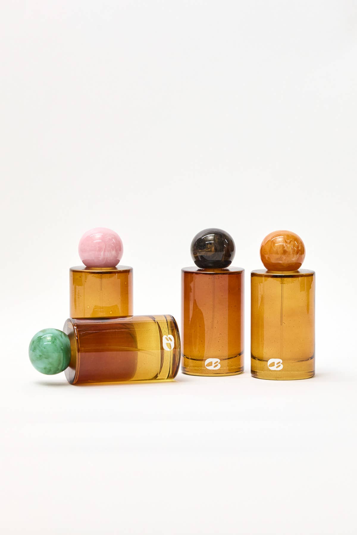 Set of amber glass bottles with colorful spherical tops on a white background