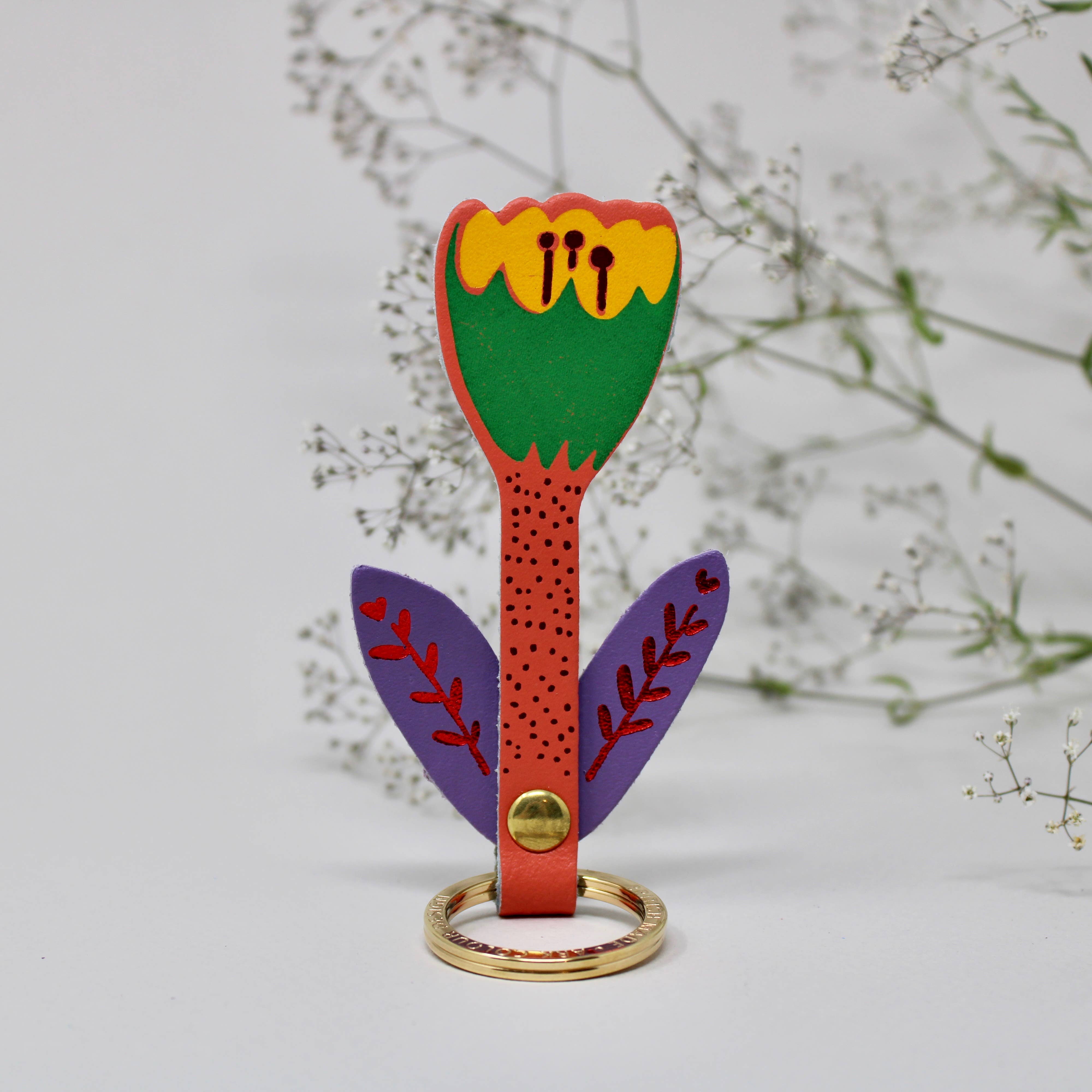 Colorful tulip keychain behind foliage background. 