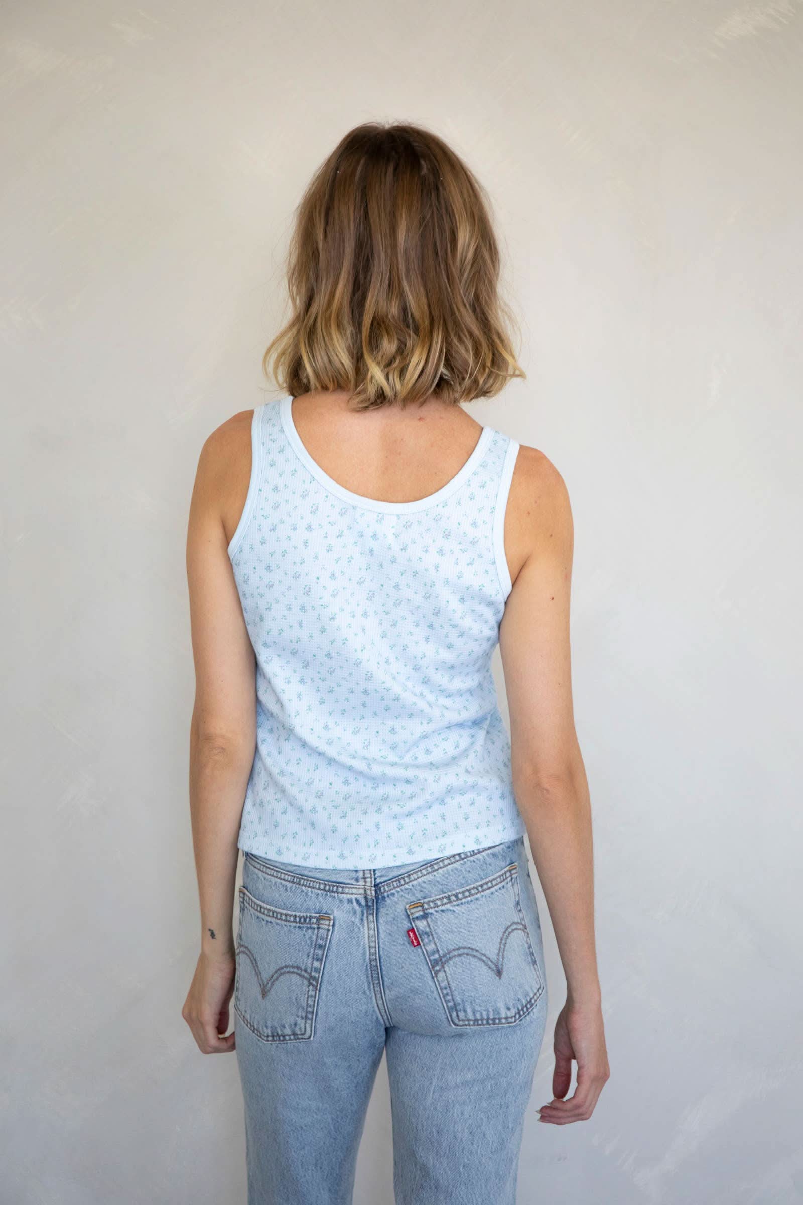 Woman wearing Waffle-knit henley tank top with a floral design in baby blue 