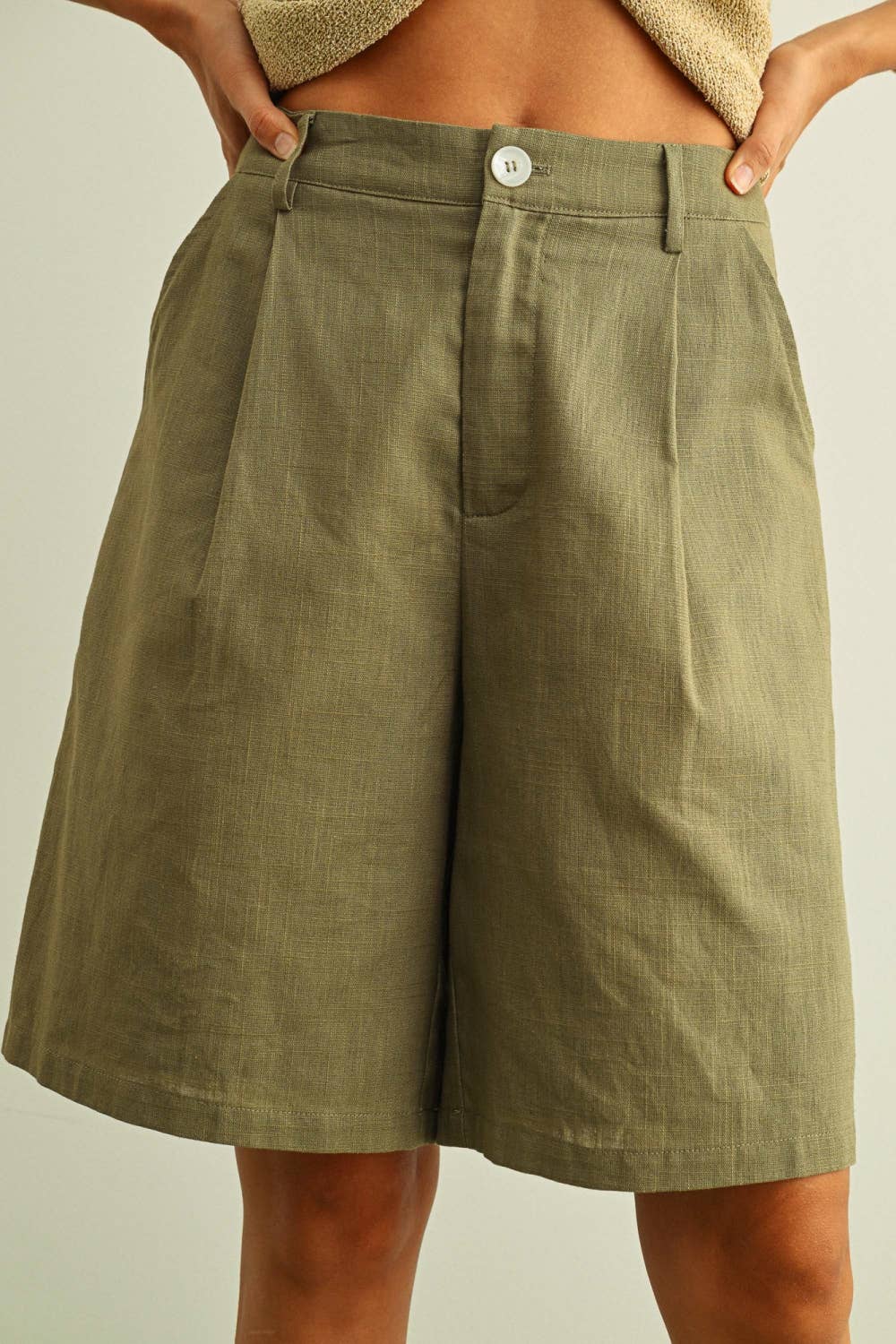 Person wearing olive green shorts on a plain background