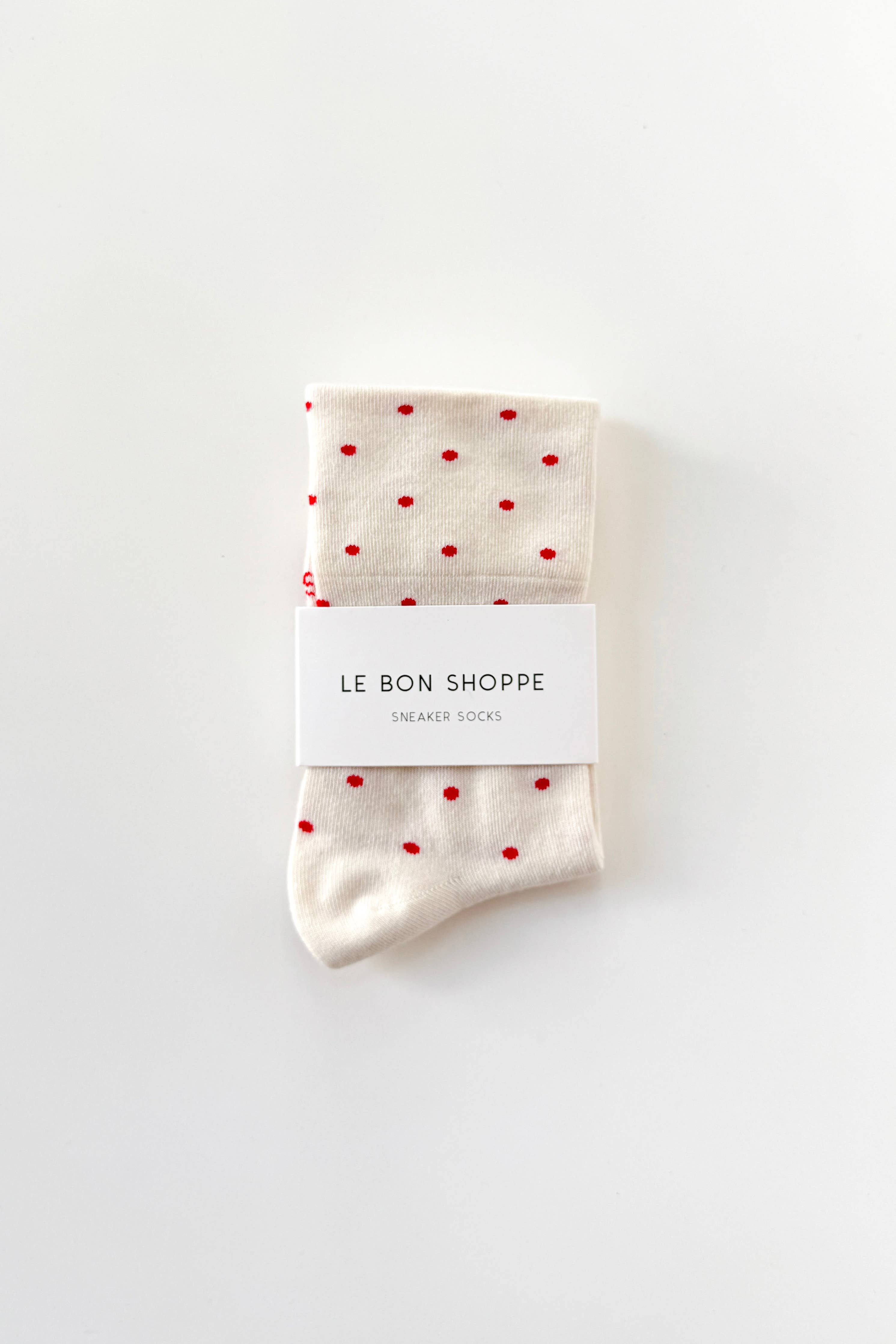Pair of socks with red polka dots and a visible brand label on a white background