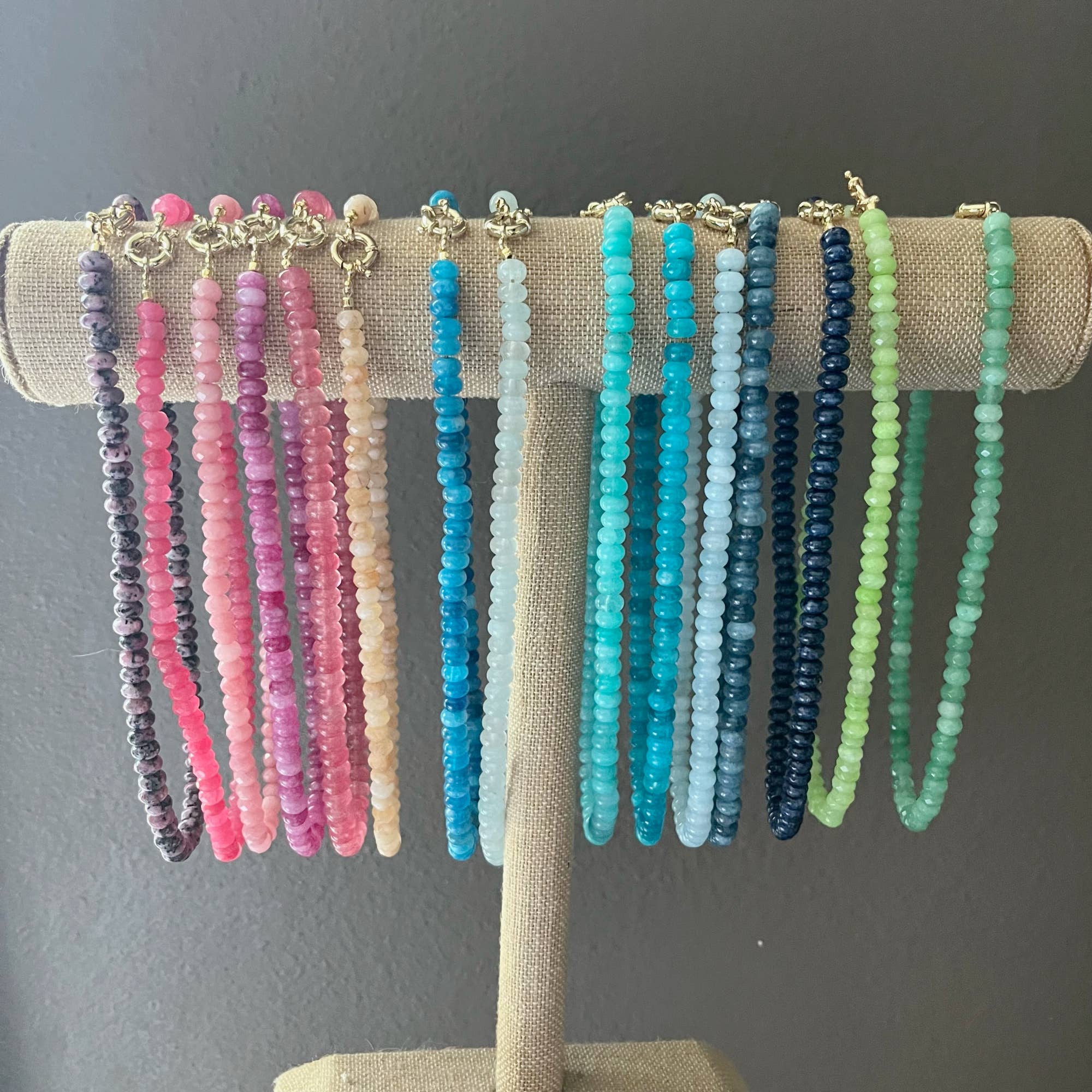 Set of colorful beaded necklaces on a display stand against a gray background