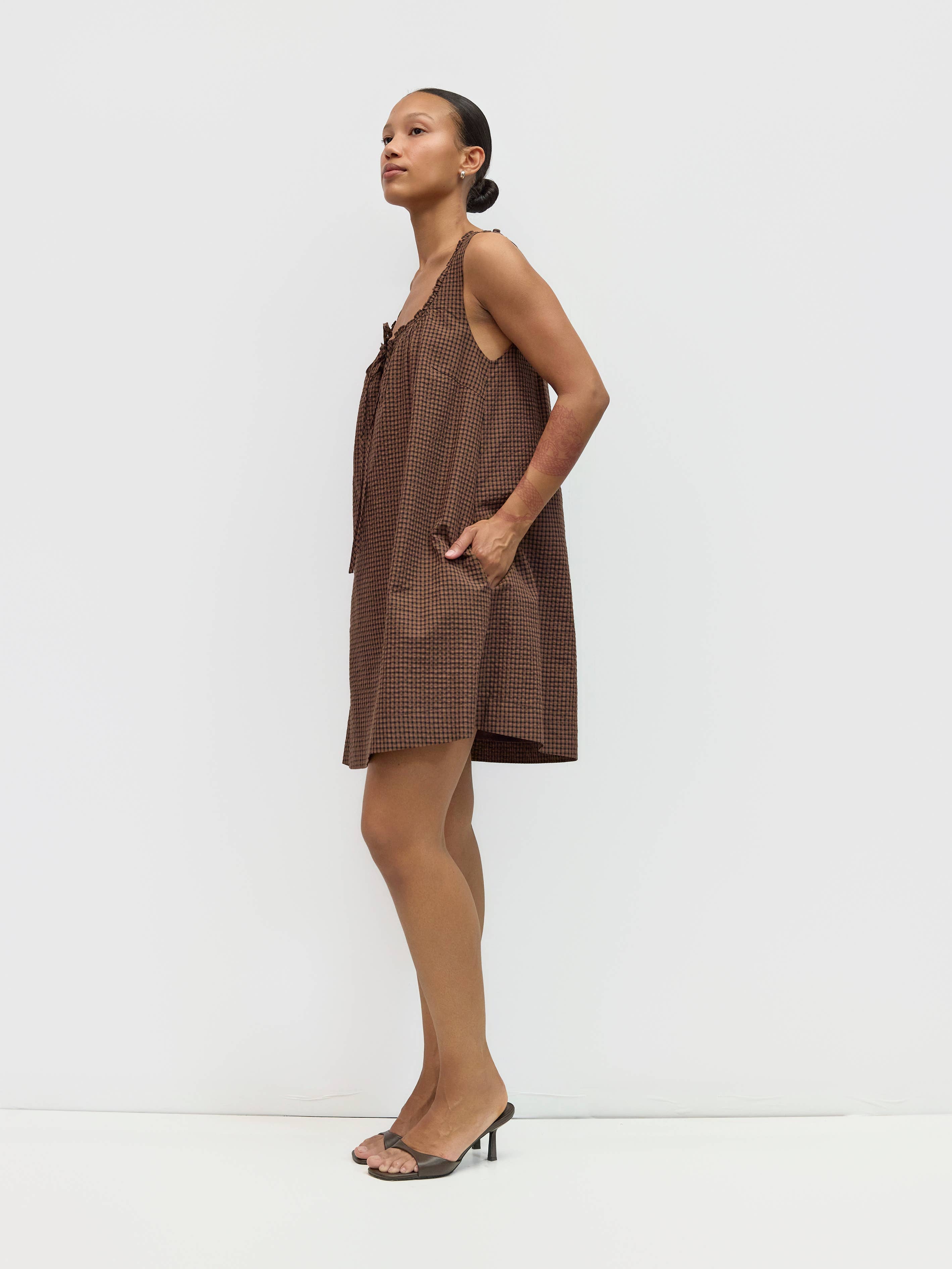 Woman wearing a brown checkered dress against a white background