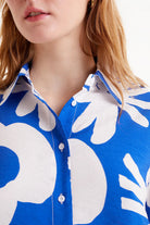 Woman wearing large print button up blouse in white and blue zoomed in at collar 