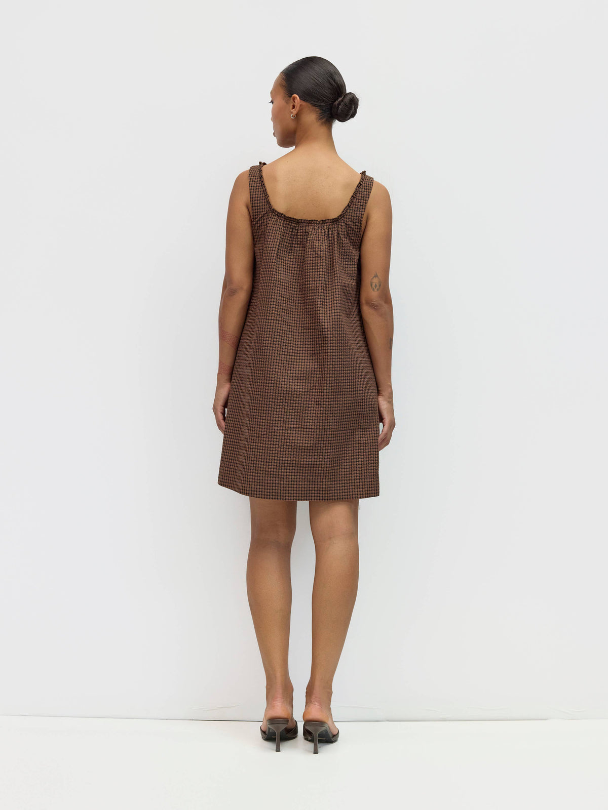 Woman wearing a brown checkered dress against a white background