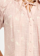 Close up details of pink flowy blouse with tulip embroidery details