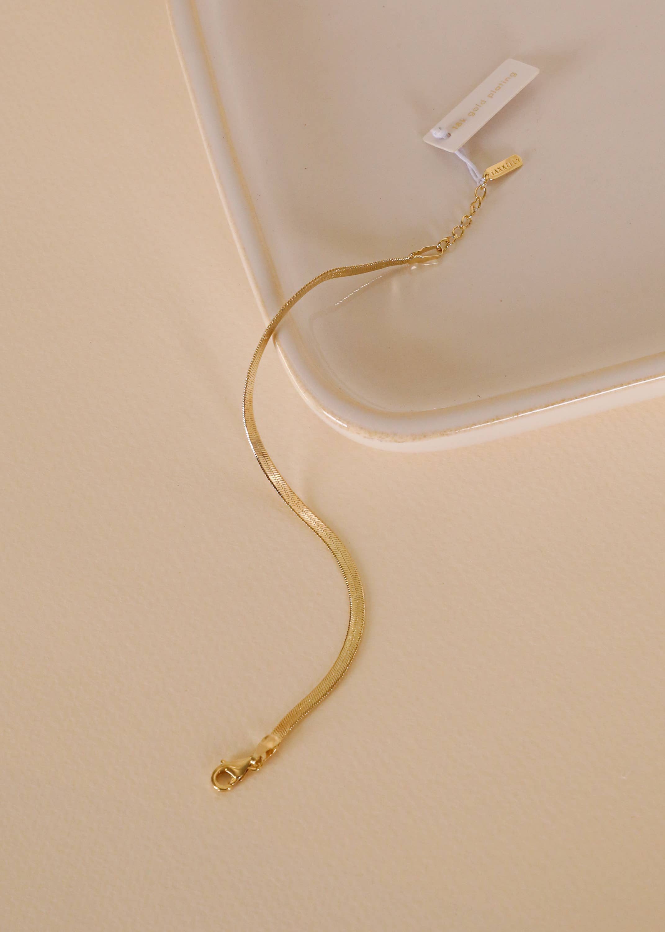Gold bracelet on a beige surface with a white background