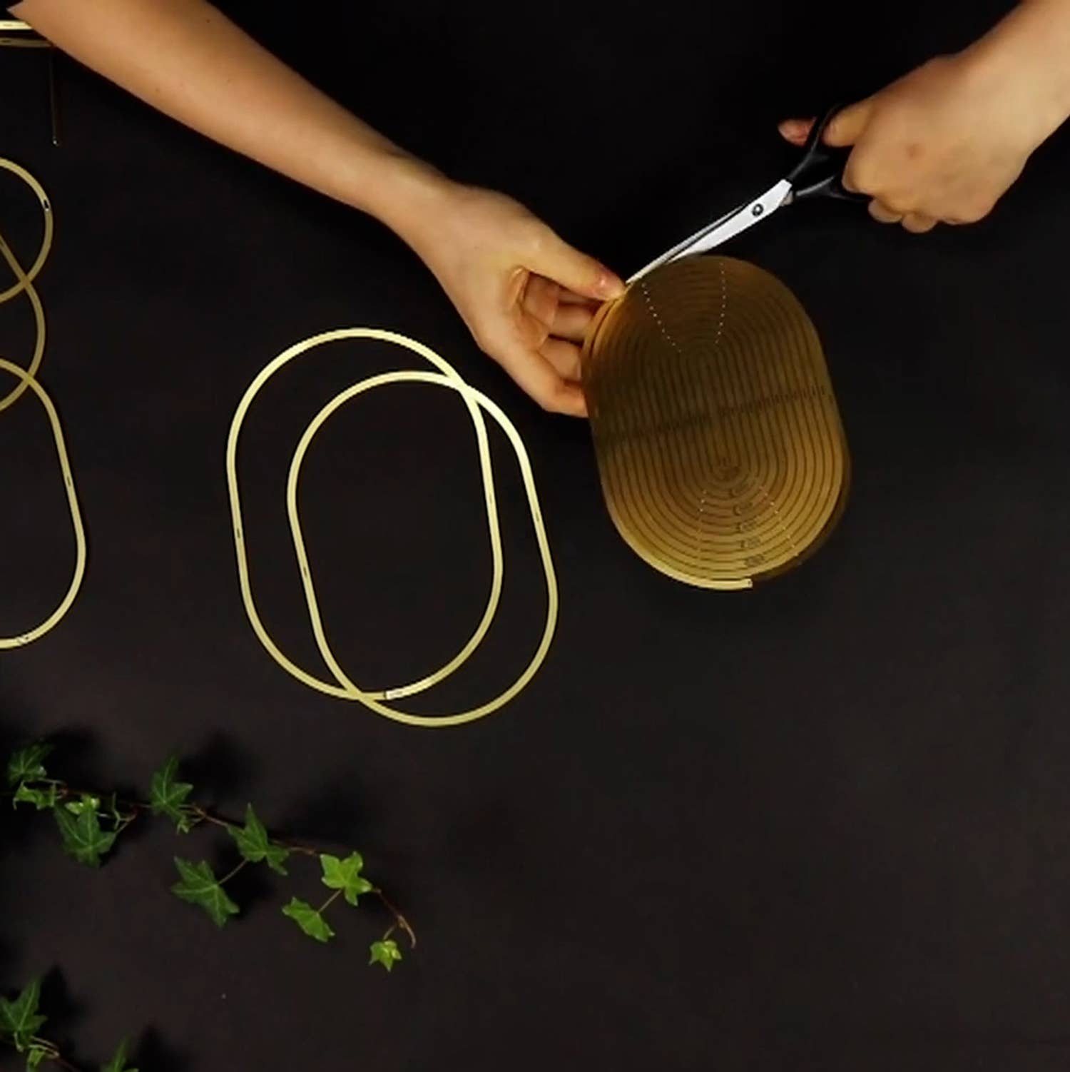 Person cutting a woven basket with scissors on a dark surface