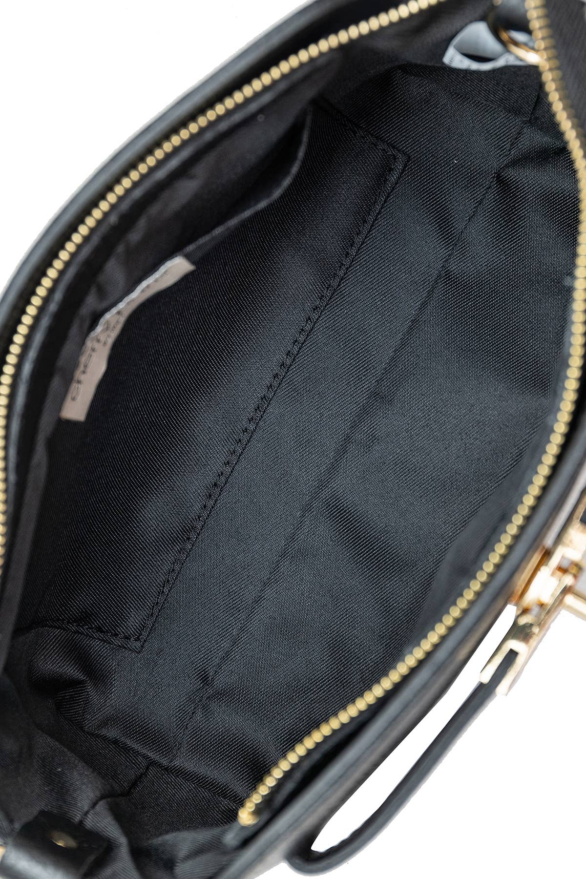 Close-up of the interior of a black handbag or clutch, showing a black fabric lining, a zippered opening with gold-tone zipper teeth, and part of the exterior material at the top right.