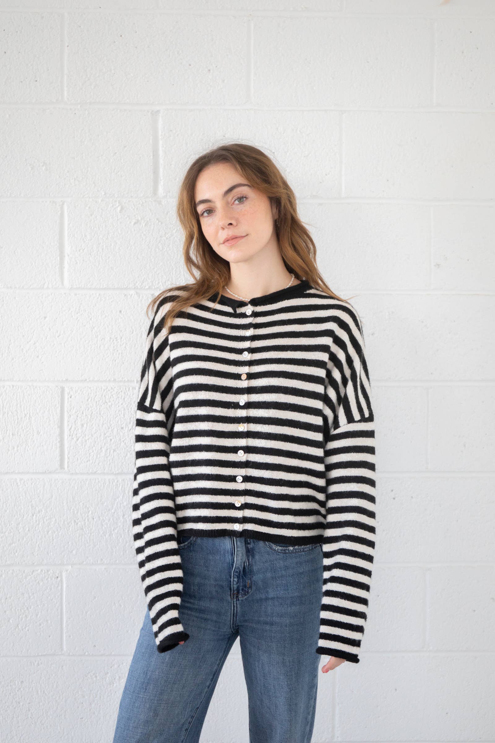 Woman wearing a black and white striped shirt against a white brick wall