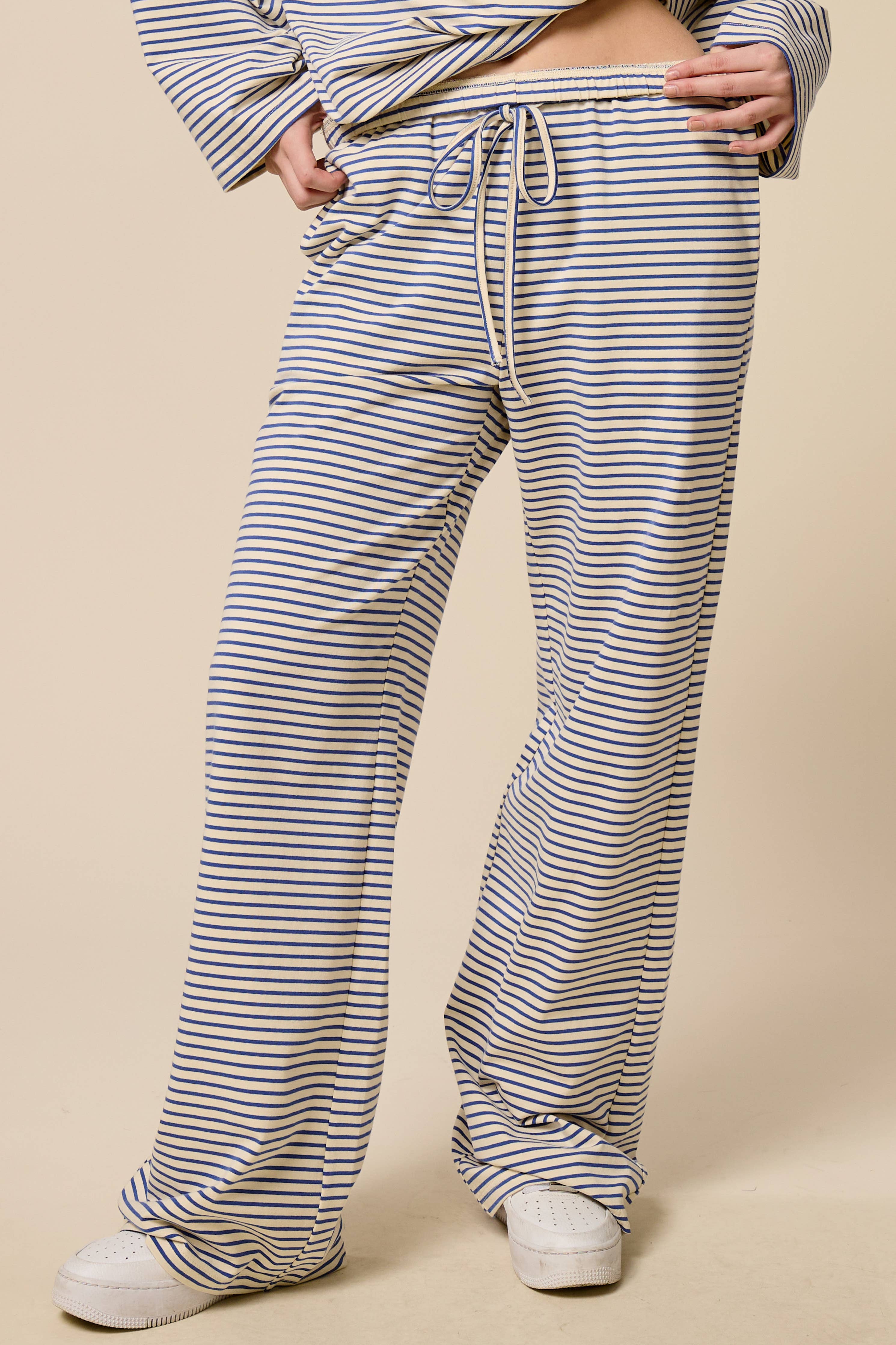 Person wearing blue and white striped pants on a beige background