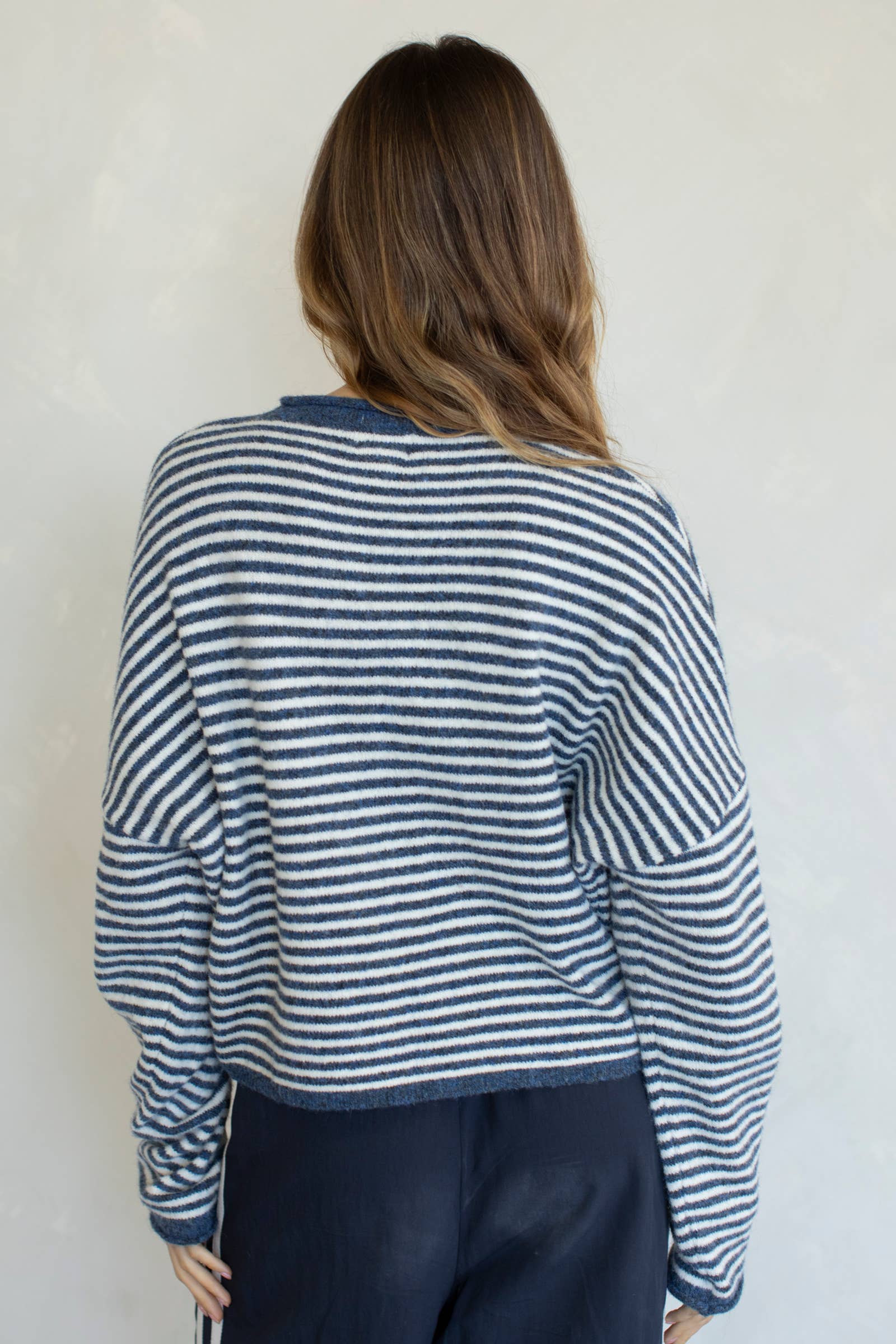 Person wearing a blue and white striped sweater against a plain background