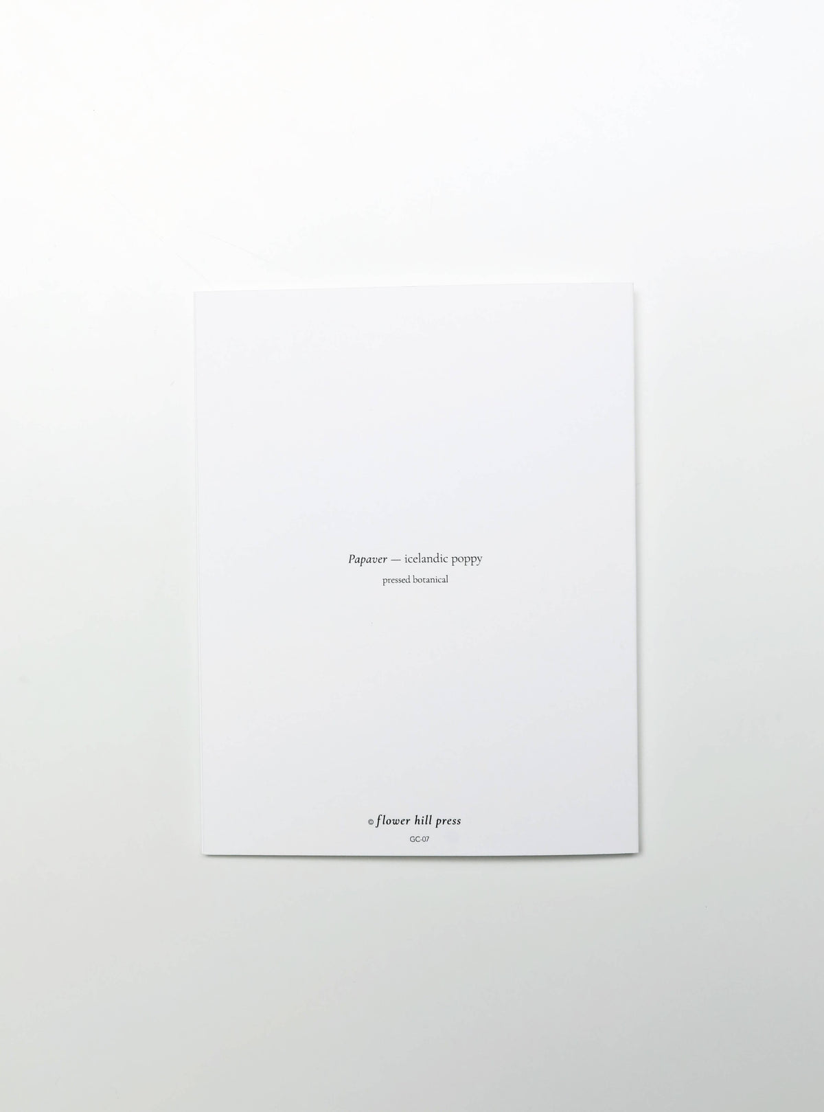 A minimalist white art print or card with small black text centered on a white background, photographed from above.