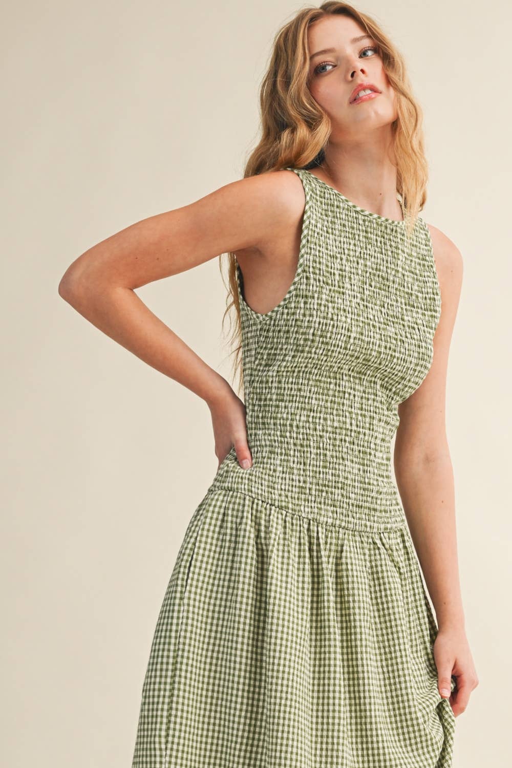 Woman wearing a green checkered dress against a plain background