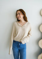Woman wearing blue jeans, and a natural beige button up piper cardigan 