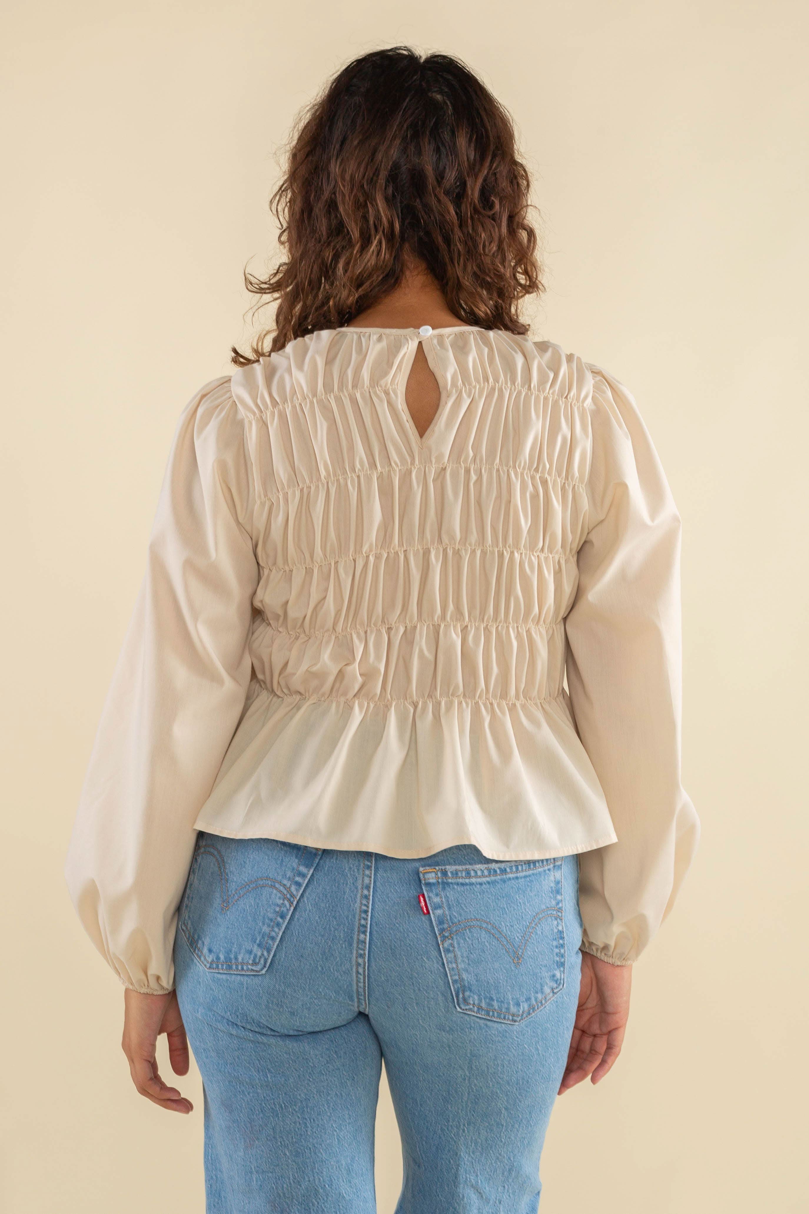 Woman wearing natural cream white color, bubble long sleeve, shirred, peplum style top