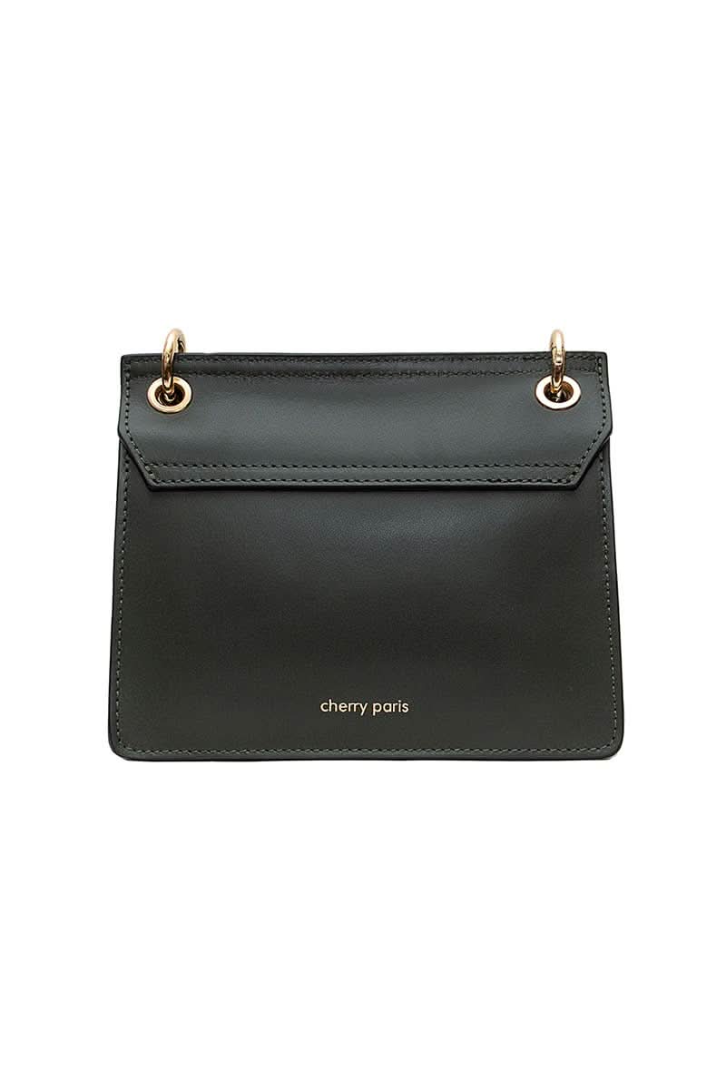 Black leather handbag with gold details and clasp sitting against white background with “cherry Paris” written in gold on the back