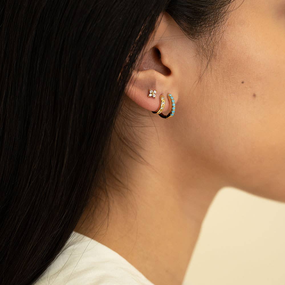 Close-up of an ear wearing gold hoop earrings with a blurred background