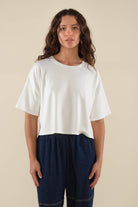 Woman wearing white, short sleeve, jersey, cropped t-shirt and blue jeans 