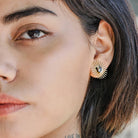 woman wearing sunburst and black stone layered gold earrings 