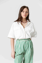 Woman wearing white shirt and green and white, vertically striped pants