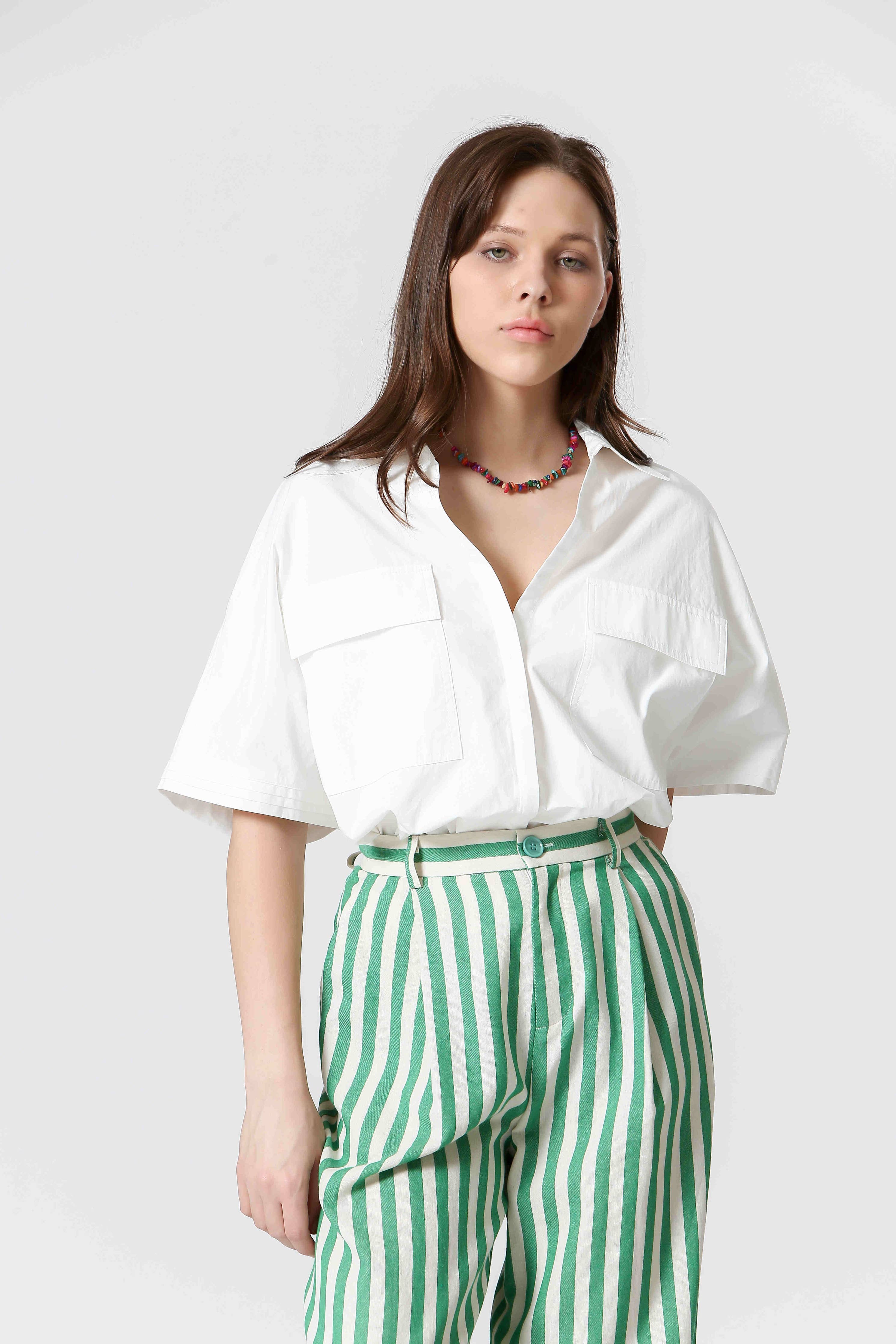 Woman wearing white shirt and green and white, vertically striped pants