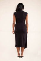 Woman wearing black, Mock neck, midi dress with off shoulder sleeves with front tie skirt detail.