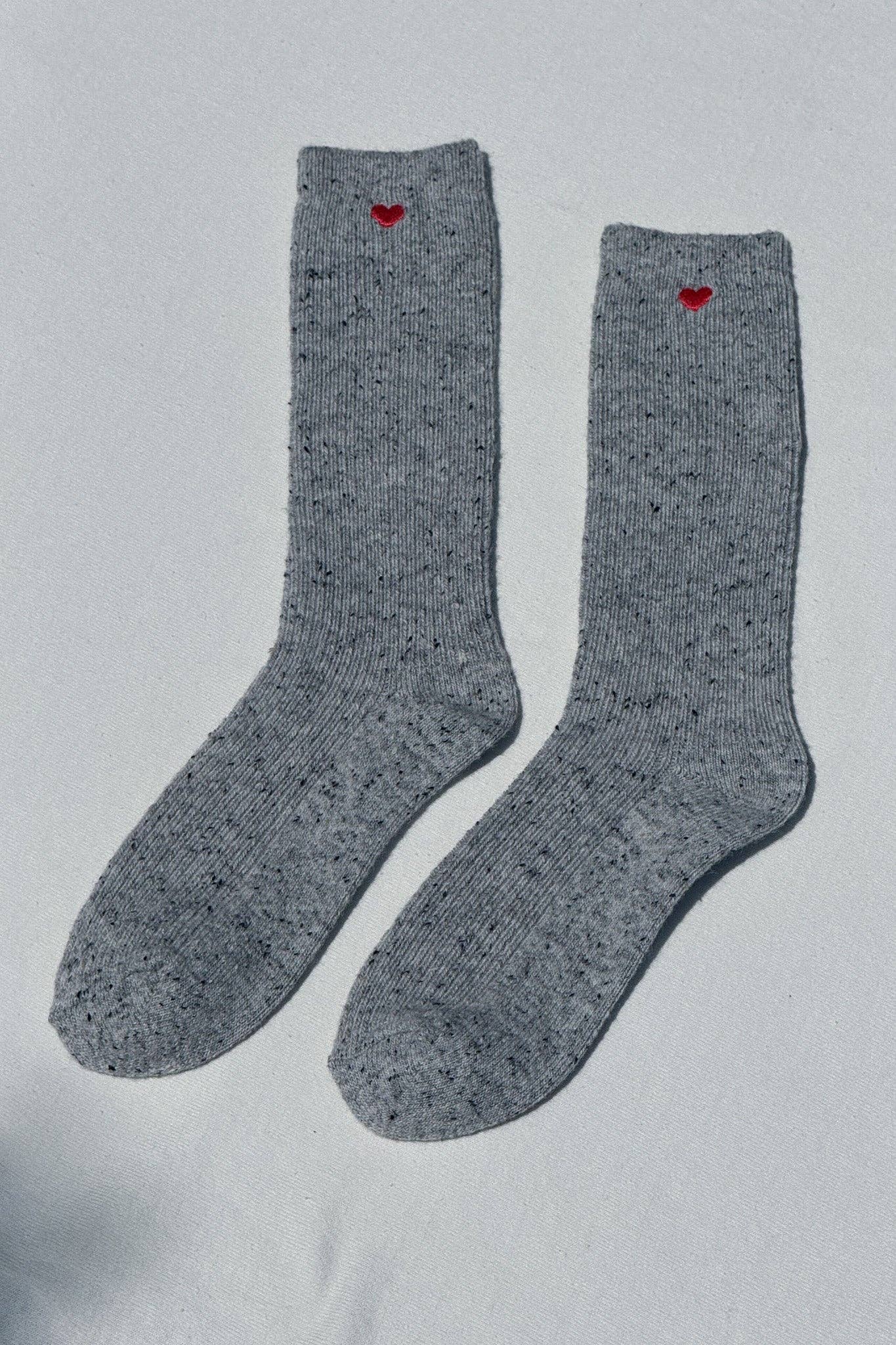 Pair of gray socks with red hearts on a light gray background