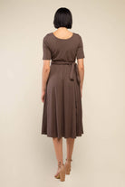 Woman facing away from the camera wearing high heels and brown midi ribbed dress with waist adjustable tie at waist