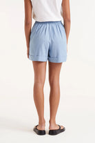 Woman wearing denim like chambray shorts with white sleeveless top 