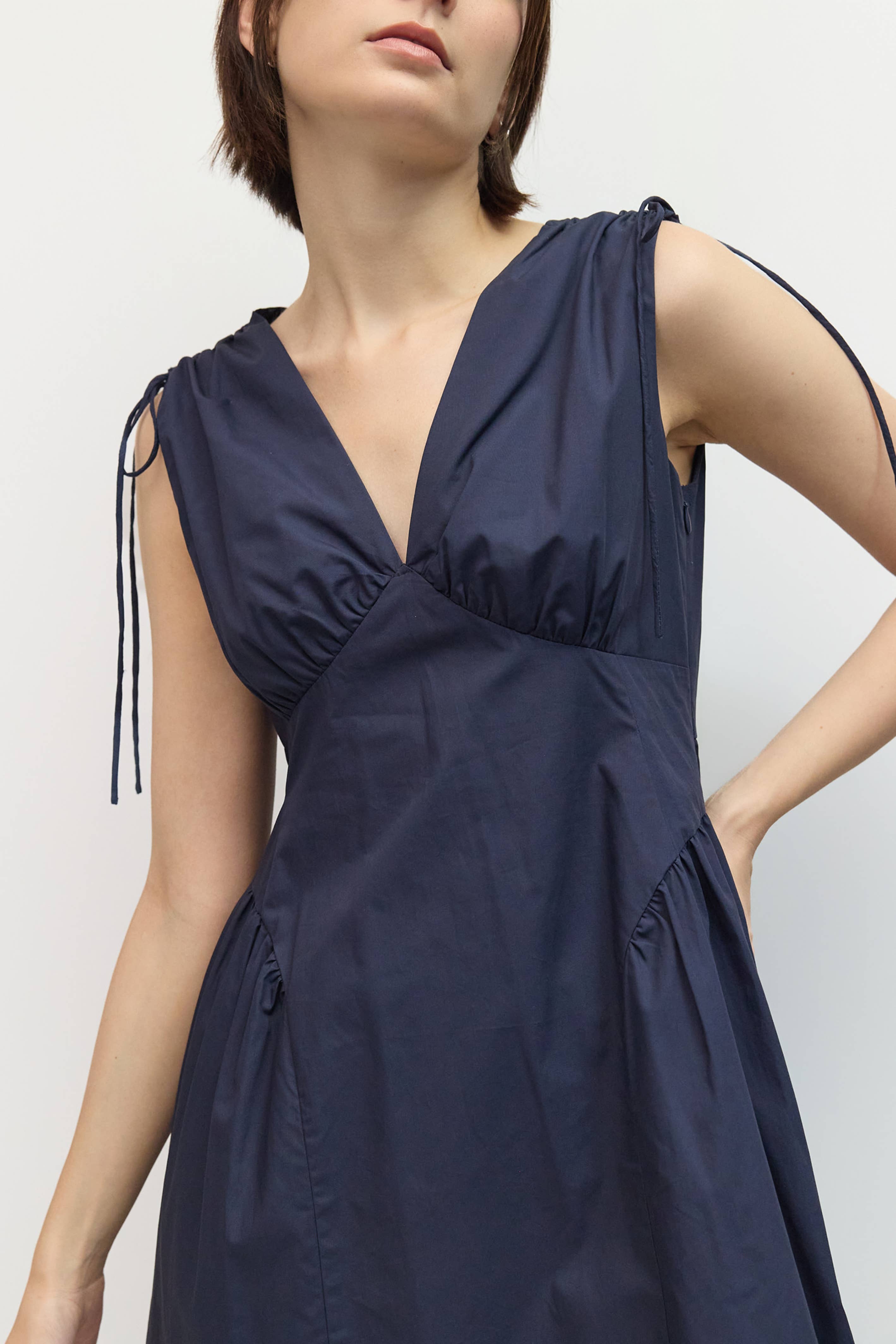 Navy blue dress with shoulder straps on a plain background