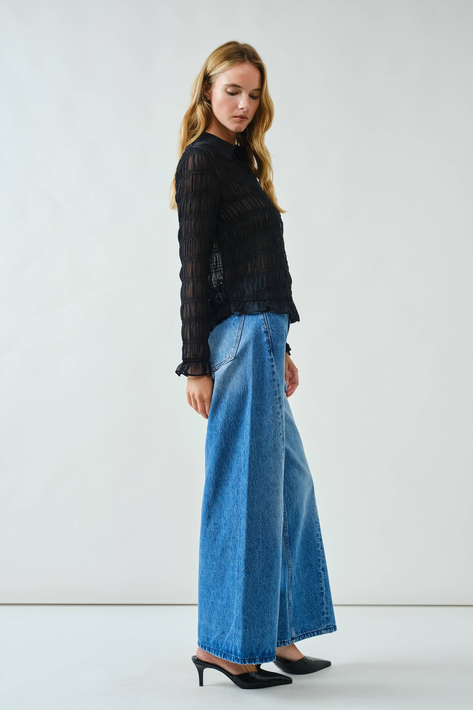 Woman wearing a black top and blue jeans on a white background