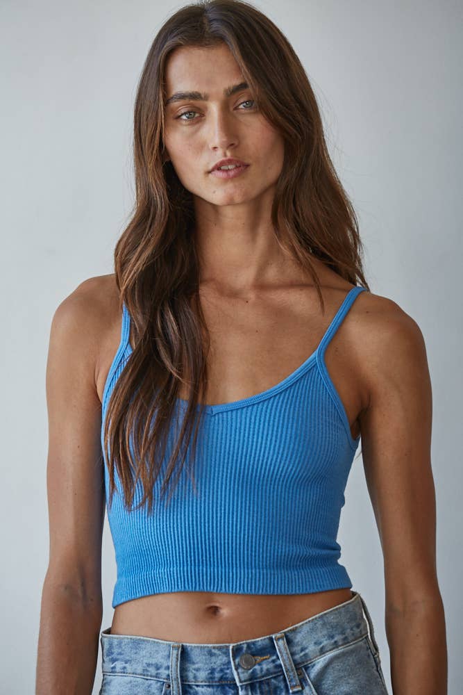 Woman wearing a blue ribbed tank top against a plain background
