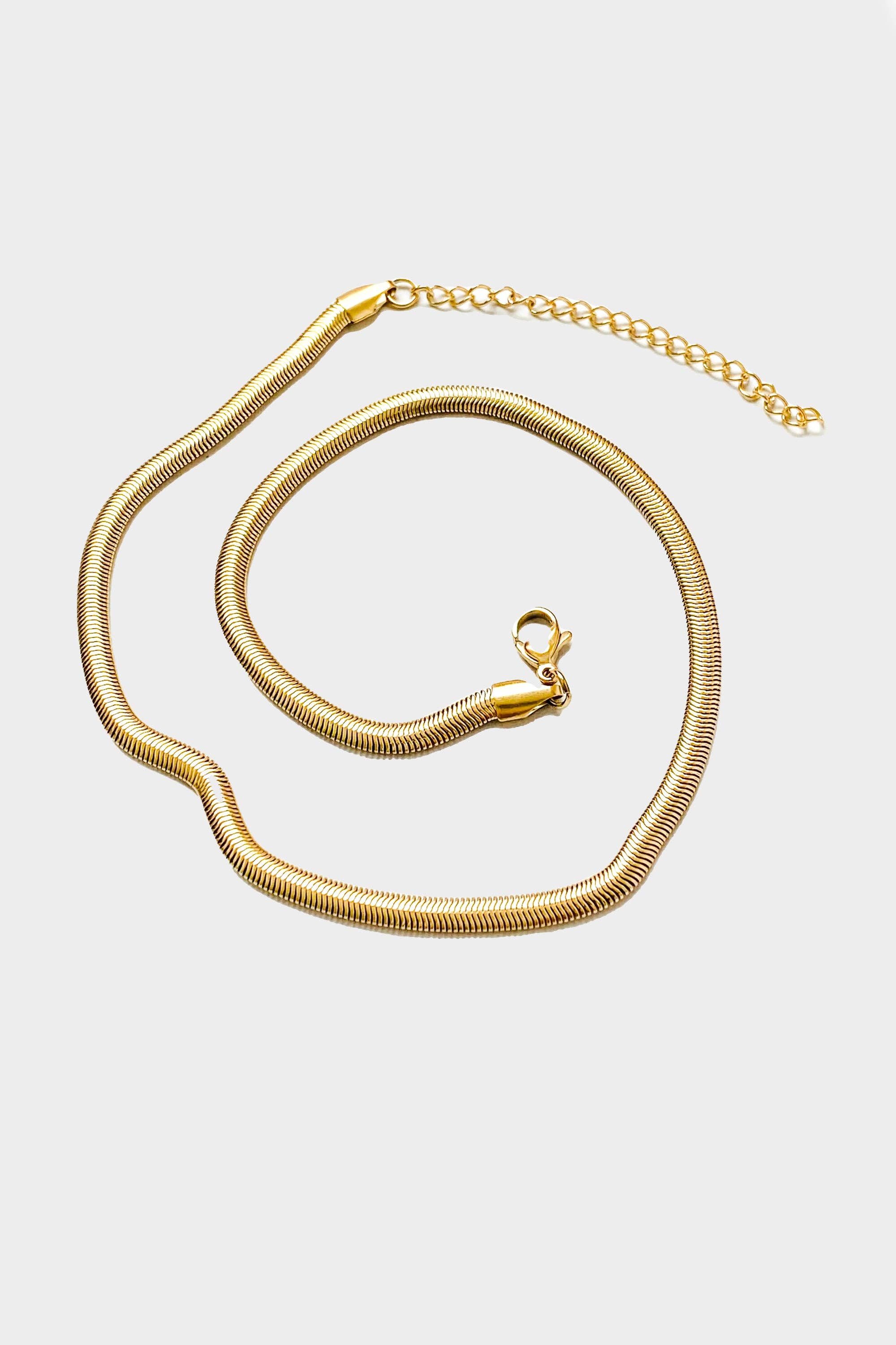 18k gold 15 inch to 17 inch herringbone necklace laid out in a swirl pattern on white background 